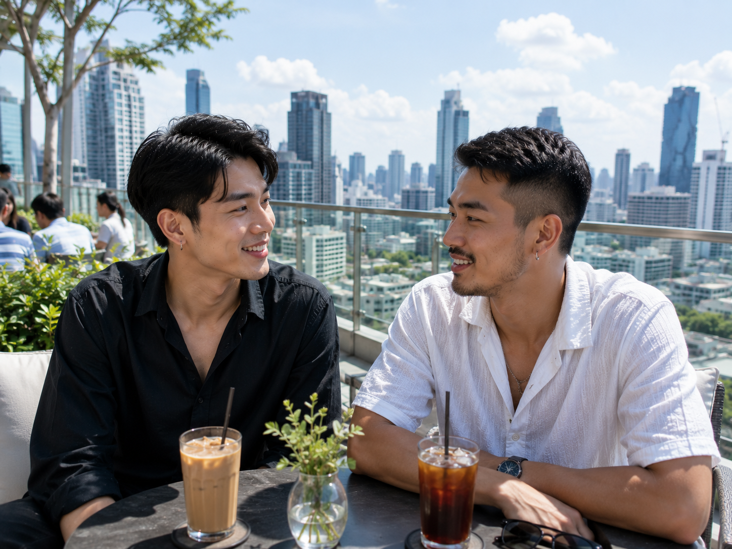 ชายหนุ่มสองคนกำลังพูดคุยและยิ้มให้กันบนคาเฟ่ดาดฟ้ากลางกรุงเทพฯ ในช่วงกลางวัน โดยมีวิวตึกสูงและเส้นขอบฟ้าของเมืองเป็นฉากหลัง สื่อถึงการทำความรู้จักคนใหม่และการสร้างความสัมพันธ์ในบรรยากาศที่ผ่อนคลายและเป็นกันเอง